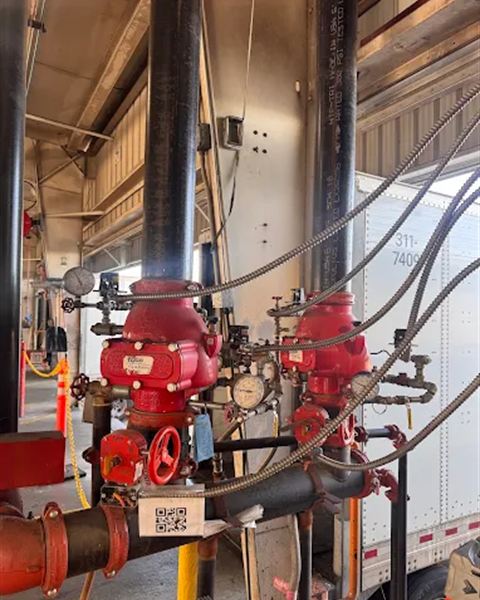 Two red dry pipe sprinkler risers with gauges in a warehouse loading area