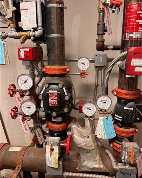 Sprinkler riser room with alarm valves, gauges, and inspection tags